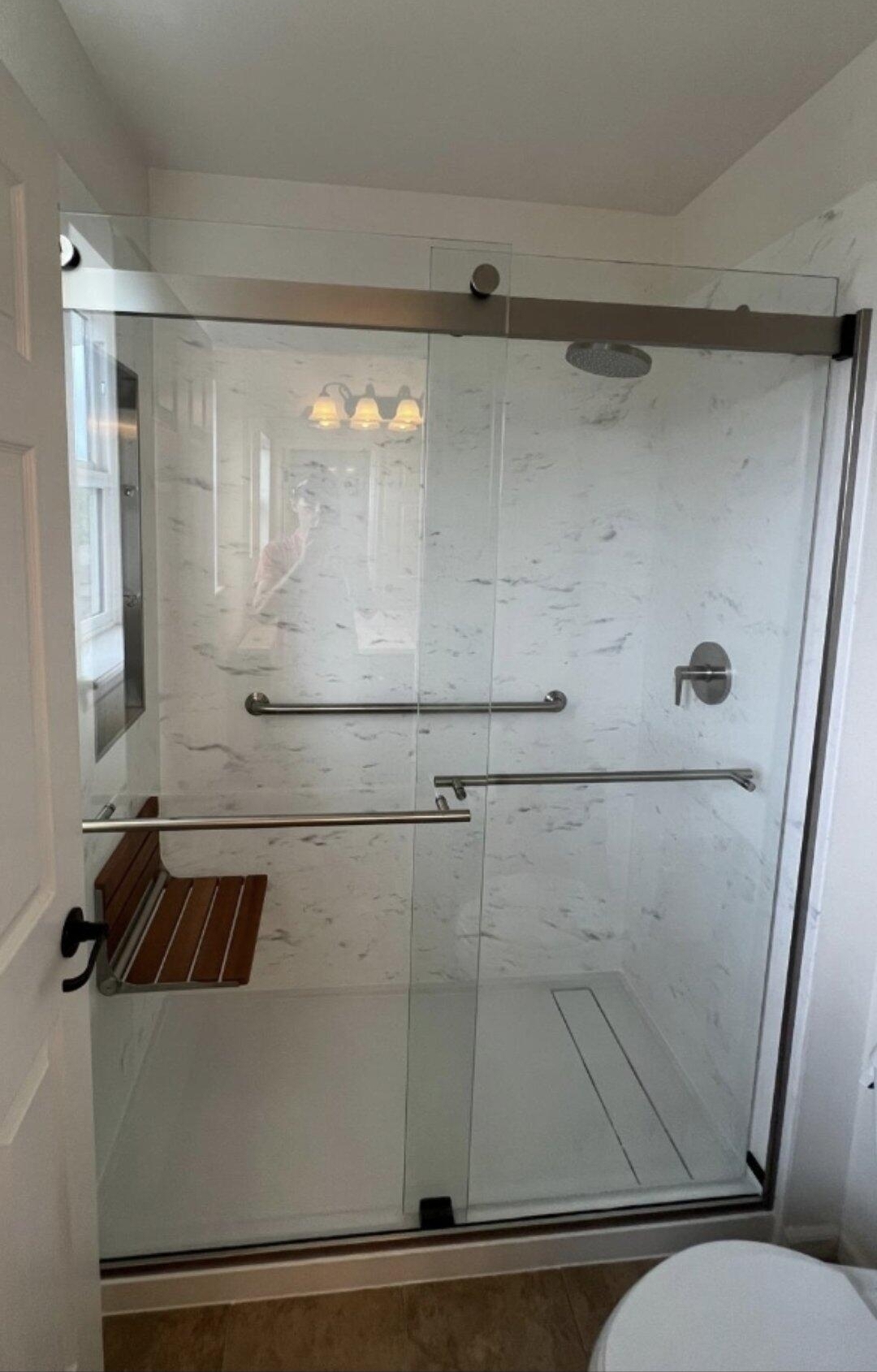 Walk-in shower with teak bench and marble-look stone walls
